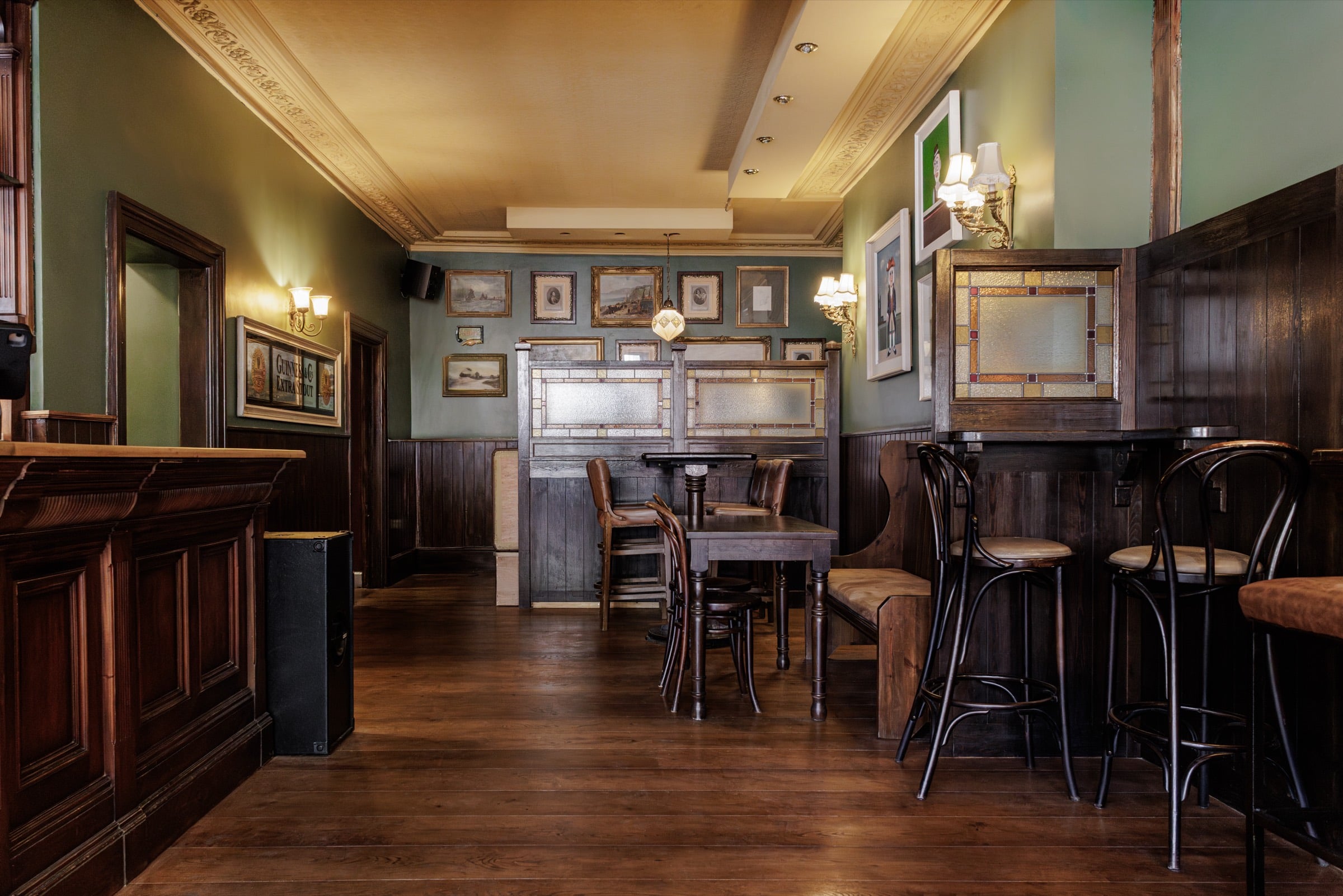 A snug at The Beehive, with stained-glass booth screens, framed paintings and bentwood bar stools